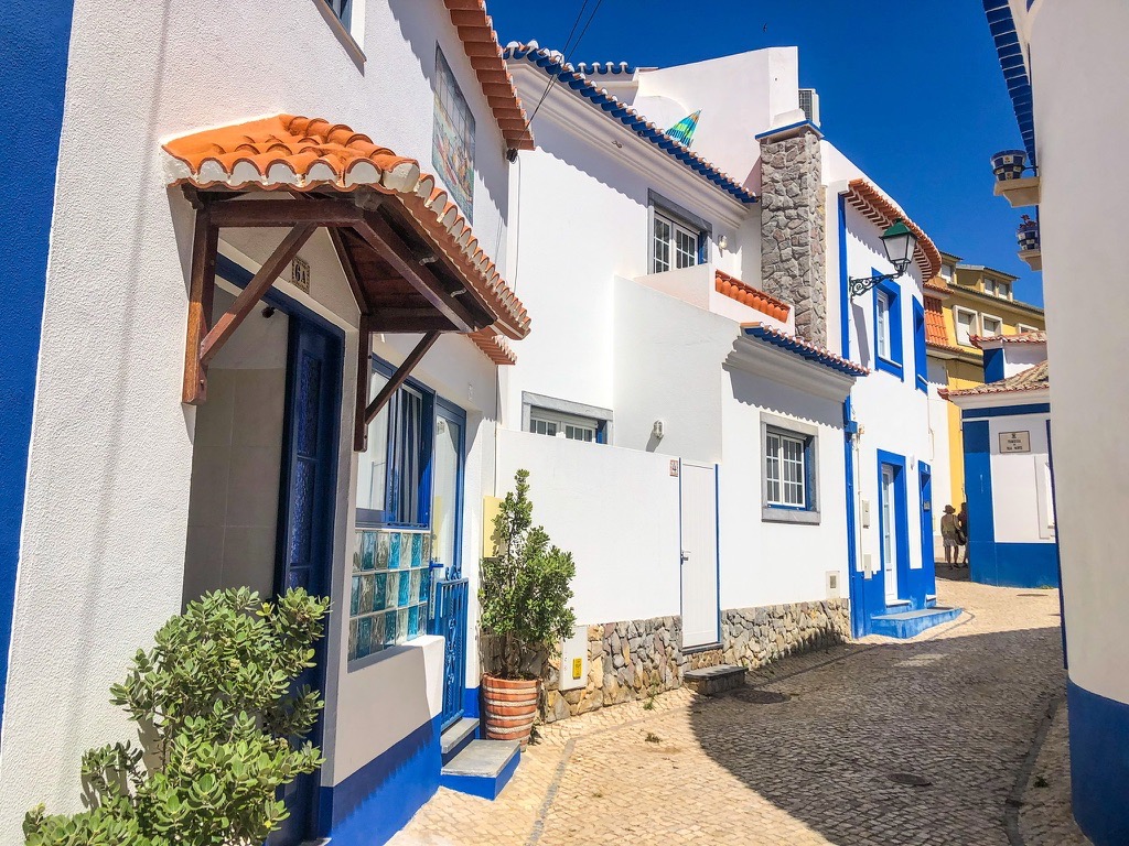 White and blue buildings in Ericeira town with cobblestone streets and orange roof tiles